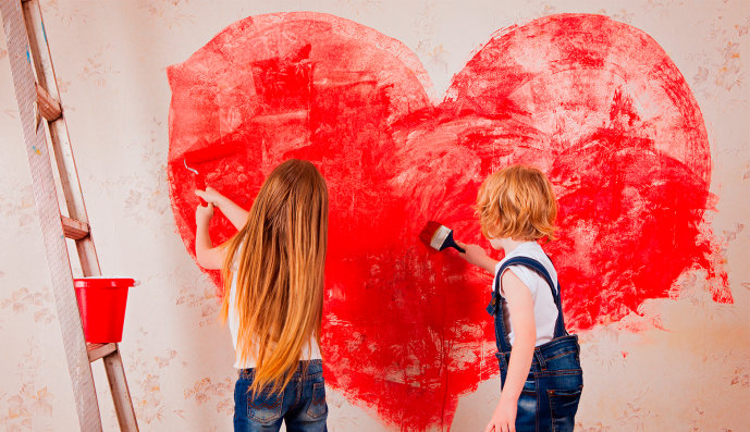 Foto: Ein Mädchen und ein Junge malen mit einer Farbrolle und Pinsel ein großes Herz an eine Wand