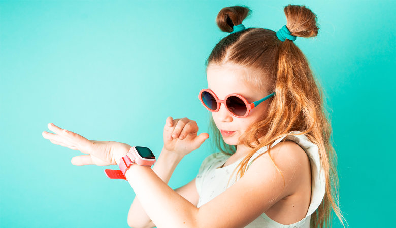 Foto: Mädchen mit Sonnbrille schaut auf ihre digitale Uhr am Handgelenk