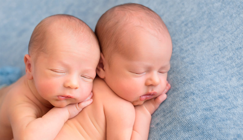 Foto: Zwei Neugeborenen Zwillinge liegen aufeinander und schlafen.