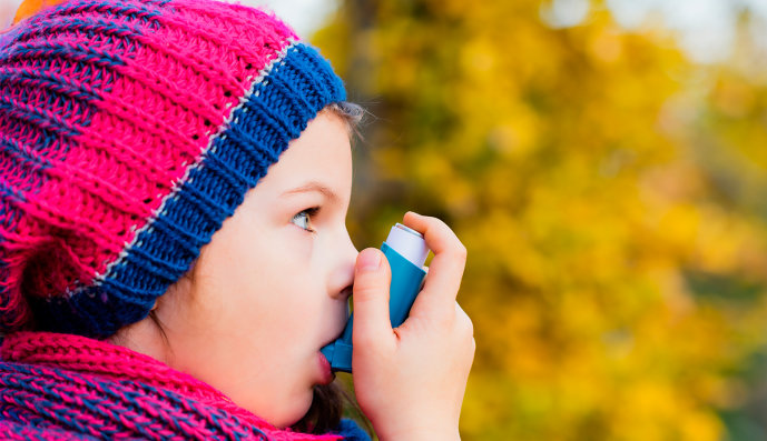 Foto: Mädchen hält sich einen Asthma-Inhalator in den Mund.