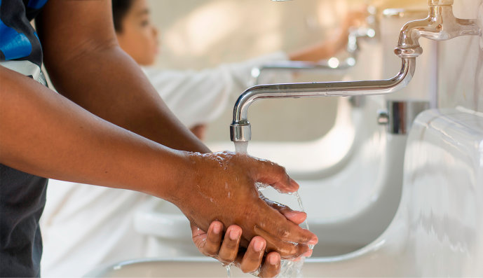 Foto: Nahaufnahme von Händen eines Kindes und eines Wasserhahnes beim Händewaschen und fließendem Wasser.