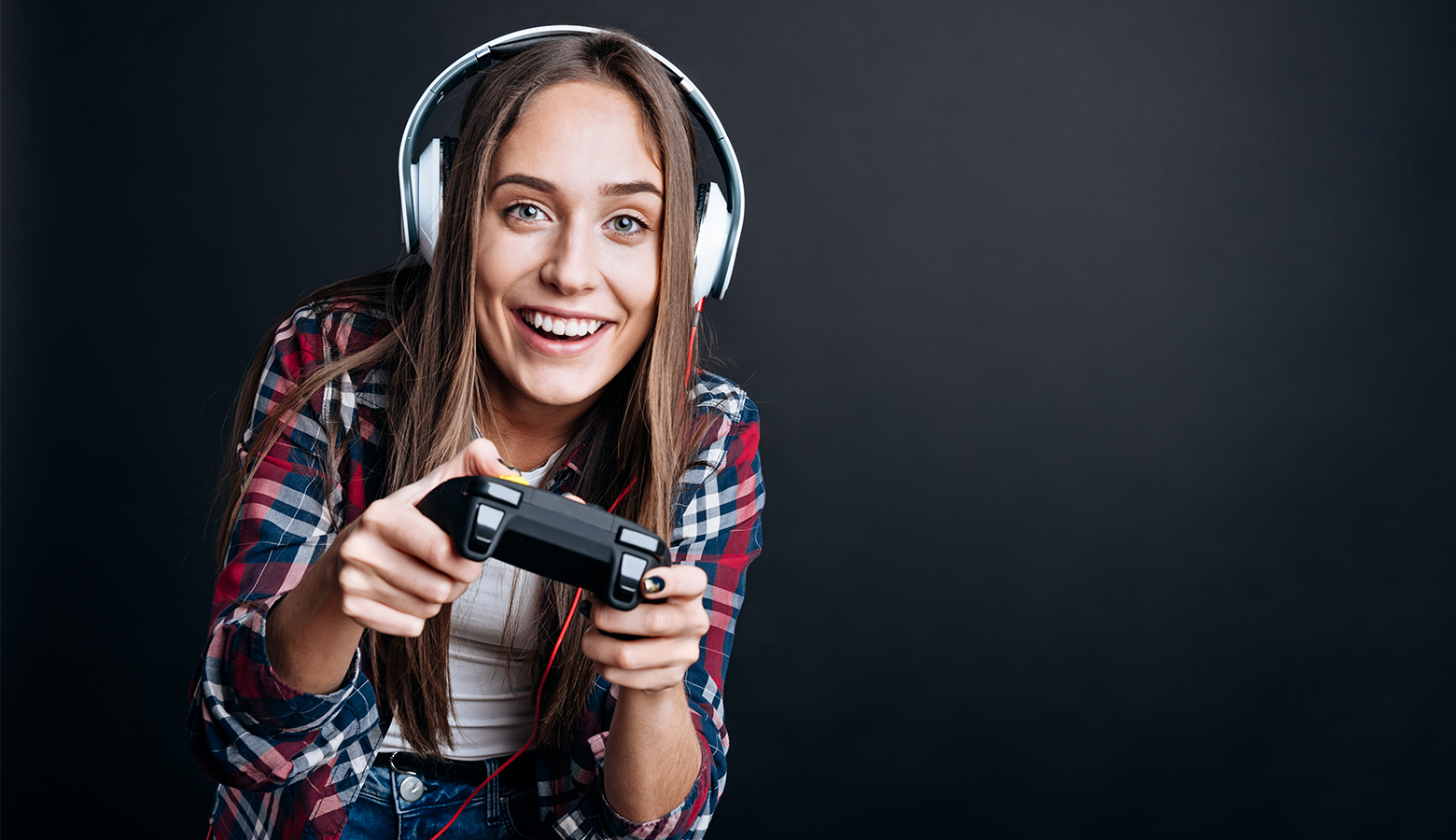 Foto: Fröhliches Teenager Mädchen mit Kopfhörern auf hält einen Joystick in der Hand