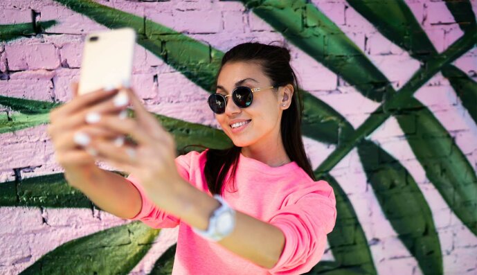 Jugendliches Mädchen mit Sonnenbrille macht mit dem Smartphone ein Selfi