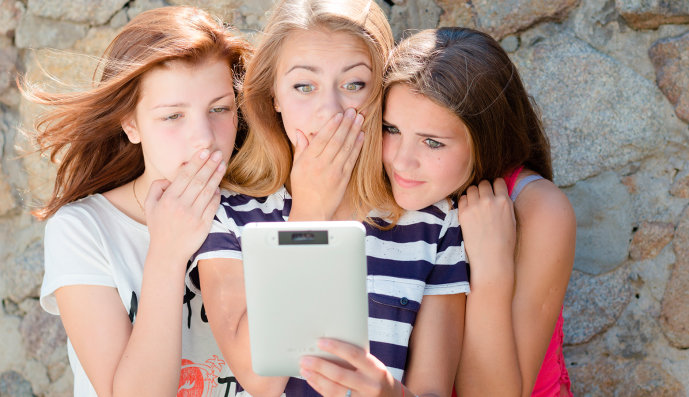Foto: Drei Mädchen, die erschrocken auf ein Tablet schauen