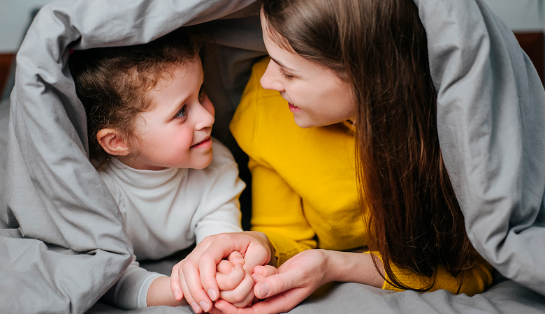 Foto: Mutter führt mit ihrem Kind ein vertrautes Gespräch unter der Bettdecke